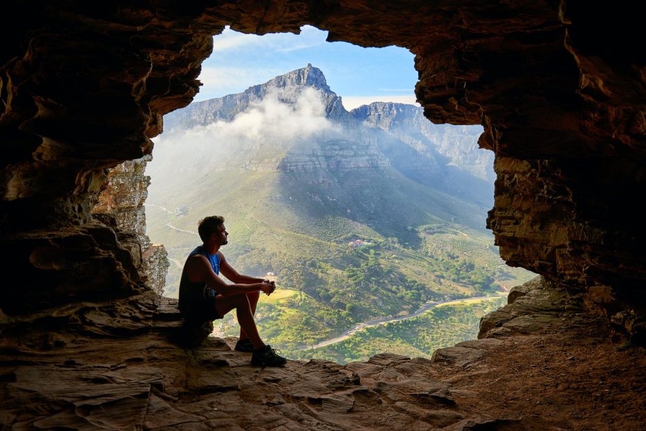photo of man sitting on a cave