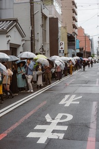 people with umbrellas in rain on japanese street