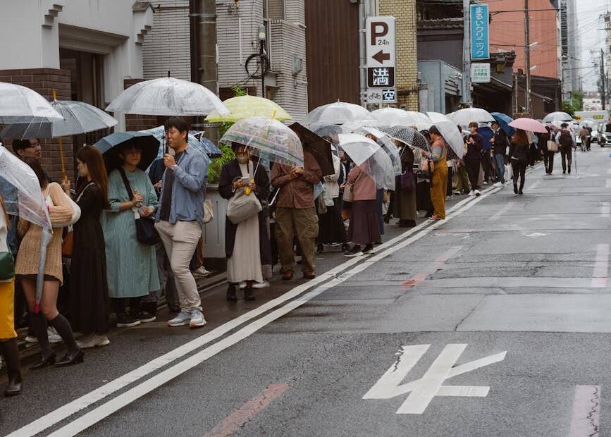 people with umbrellas in rain on japanese street