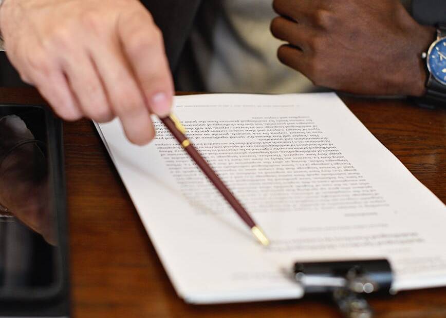 a close up shot of a person pointing on a document using a pen